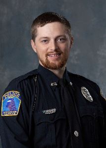 headshot of male with brown hair and bead in a police uniform