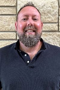 Headshot of male with light facial hair in a dark shirt
