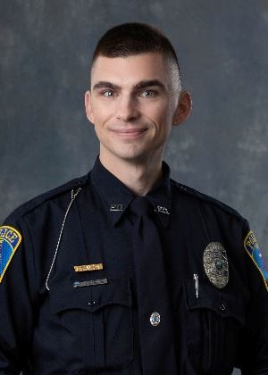 headshot of a male with short brunette hair in police uniform